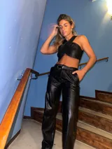 Top negro de cuerina con textura croco, corte irregular y tiras anchas cruzadas en el frente.