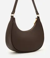 Cartera tipo baguette confeccionada en PU negro con acabado liso, cierre de cremallera superior, asa ajustable y detalles metálicos en tono dorado claro con placa de la marca al frente.