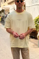Remera oversize de manga corta en color amarillo, con cuello redondo y una pequeña estampa frontal con texto en el pecho.