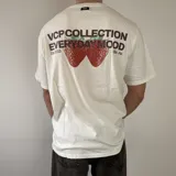 Remera blanca de corte regular, con estampa en la espalda que presenta la leyenda "VCP COLLECTION EVERYDAY MOOD" junto a un gráfico de fresas.