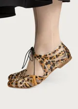 Ballerinas planas con diseño de rejilla y estampado animal print, con detalles de tiras cruzadas y borlas en el empeine.