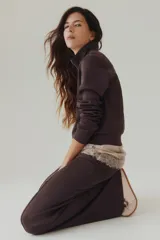 Pantalón de corte holgado en punto pesado con leve brillo, color marrón, con elástico revestido en la cintura, bolsillos al bies y piernas rectas con pliegues cosidos.