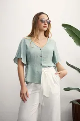 Camisa negra con botones dorados, escote en V y mangas cortas amplias con lazos laterales. 