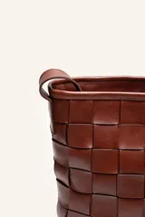 Cartera tipo morral de cuero color beige, con diseño trenzado artesanal, correa larga regulable y cierre superior.
