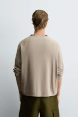 Jersey de manga larga, cuello redondo y calce relajado, color negro con efecto lavado y textura tejida.