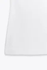 Top blanco de manga sisa con cuello redondo y corte ajustado al cuerpo.