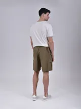 Bermuda de gabardina color verde militar, con cintura elástica ajustable con cordón, bolsillos laterales y bolsillo cargo con solapa en la pierna.