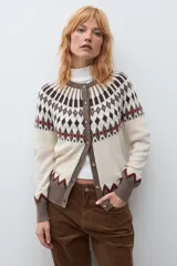 Cardigan de punto con diseño jacquard en tonos beige, marrón y rojo. Presenta cuello redondo, cierre frontal con botones y puños acanalados.