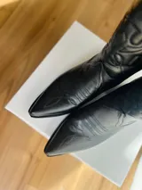 Botas texanas negras de cuero con bordados decorativos y taco bajo.