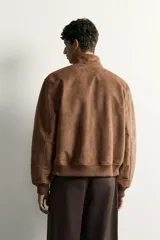 Cazadora bomber de corte regular fit en tejido efecto ante de color marrón oscuro, con cuello alto, cierre frontal de cremallera y bolsillos laterales de vivo.