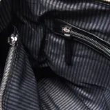 Cartera tipo hobo de cuero negro, con cierre superior, herrajes metálicos plateados y correa de hombro con detalle trenzado. Presenta el logo de la marca XL grabado en el frente.