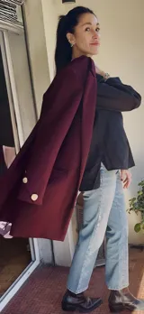 Tapado negro de lana y cashmere, de corte recto y largo a la rodilla, sin botones frontales. Tiene puños cruzados con botones dorados.