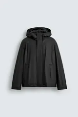 Parka de tejido técnico con acabado efecto engomado, cuello subido con capucha, cierre frontal con cremallera oculta por solapa con botones a presión, bolsillos de vivo en la cadera y mangas largas con puños ajustables.