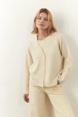 Cárdigan color crema de tejido de punto industrial con escote en V, combinación de puntos y botones decorativos en las mangas.