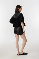 Top negro de cuero de oveja y gamuza de cabra, con cuello camisero, apliques tribales y cartera escondida con botones.