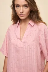 Blusa celeste de manga corta con cuello camisero y escote en V, confeccionada en tejido liviano con textura sutil y estampado de lunares.