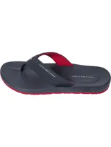 Ojotas Tommy Hilfiger azul marino con suela roja y tiras con logo de la marca.