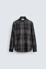 Camisa de corte relajado confeccionada en tejido fluido con mezcla de viscosa. Presenta diseño de cuadros en tonos grises y azul oscuro, cuello solapa, manga larga con puños abotonados y cierre frontal de botones.