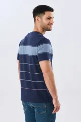 Remera de algodón con diseño de rayas horizontales en tonos azul marino, celeste y líneas finas en verde claro y amarillo pálido. Cuenta con cuello redondo y mangas cortas, con un pequeño bordado en el pecho.