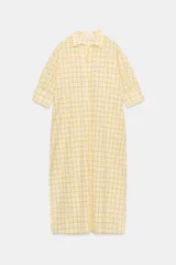 Vestido midi camisero de algodón, color amarillo con estampado a cuadros. Cuenta con cuello solapa, escote en V, mangas cortas con puño y bolsillos laterales ocultos en la costura, con diseño evasé.