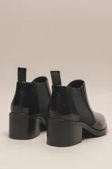 Botín chelsea de cuero vacuno color bordó con acabado charol, punta fina y elástico lateral negro. Posee un taco ancho y bajo de goma.