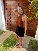 Top halter confeccionado en cuero color camel, con diseño sin mangas, espalda descubierta y ajuste mediante tiras.