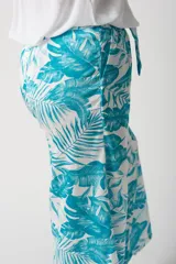 Pantalón palazo turquesa con estampado de hojas, cintura elastizada con lazo y corte amplio.