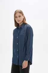 Sobrecamisa de jean en tono celeste claro, con cuello clásico, cierre frontal con botones metálicos y bolsillos frontales tipo parche.