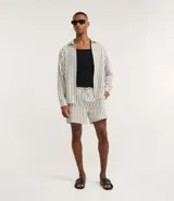 Bermuda de playa con diseño de rayas verticales, confeccionada en tejido texturizado de secado rápido. Cuenta con cintura elástica ajustable mediante cordón y bolsillos laterales.