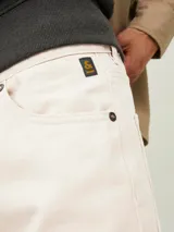 Pantalón de jean color beige, corte recto, con cinco bolsillos y cierre de cremallera.