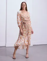 Vestido midi estampado con flores y mandalas en tonos naranja, rojo y celeste, con escote en V, mangas 3/4 con puños fruncidos, cintura elastizada con lazo y ruedo irregular.