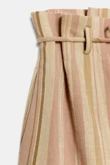 Bermuda de tiro medio con diseño de rayas verticales en tonos rosados y beige. Presenta cintura con trabillas, cinturón ajustable con lazada, bolsillos laterales y detalle de pliegues en el delantero.
