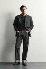 Blazer de corte regular fit color gris oscuro, confeccionado en tejido con lana. Cuenta con cuello con solapas de muesca, cierre frontal con tres botones, bolsillos con solapa en la cadera y un bolsillo de vivo en el pecho.
