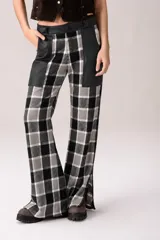 Pantalón de tiro medio con diseño de cuadros tartán en tonos marrón, blanco y negro, combinado con detalles de cuero en la parte superior y grandes bolsillos frontales.