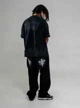 Jean negro de corte regular fit, con bolsillos traseros amplios que cuentan con un estampado gráfico en color blanco de calaveras y diseño gótico.