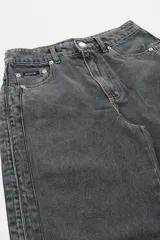 Jean de corte wide leg en denim color gris oscuro con efecto lavado. Presenta cintura alta, costuras laterales reforzadas y aberturas en el ruedo.