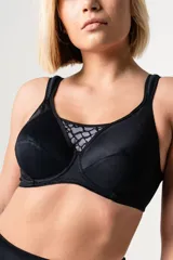 Soutien deportivo reductor negro con aro, confeccionado en jersey y tela de faja en la espalda para mayor sujeción. Breteles acolchados regulables, escote alto con detalle de puntilla y ganchos reforzados en la espalda.