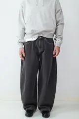 Jean de corte balloon para hombre, confeccionado en denim negro con costuras en contraste. Presenta un diseño de cinco bolsillos, cierre de botón y cremallera, con una silueta amplia y relajada.