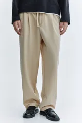Pantalón en punto de mezcla de algodón, color beige, de corte regular y piernas rectas. Cuenta con cintura elástica con cordón ajustable, bolsillos laterales al bies y bolsillos traseros de parche.