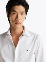 Camisa blanca de popelín de puro algodón con Flex Technology, cuello inglés, puños redondeados con botones y logo de Tommy Hilfiger bordado en el pecho.