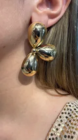 Caravanas de diseño escultórico compuestas por tres piezas metálicas con forma de gota o pétalo en acabado dorado brillante.