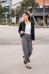 Pantalón gris de vestir con corte palazzo, tiro alto y botones dorados decorativos en los bolsillos.