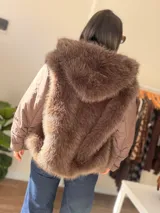 Campera puffer oversize color marrón, con paneles frontales y traseros de pelo sintético suave. Presenta mangas acolchadas, cierre frontal y bolsillo con cierre en la manga.