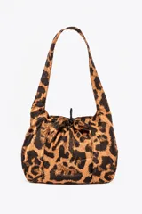 Bolso tipo hobo con estampado animal print de leopardo, con tiras para el hombro y cierre ajustable con cordón y tanca en la parte superior.