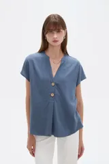 Blusa de viscosa color blanco, de corte holgado, con cuello en V y cierre frontal parcial de botones grandes con efecto carey.