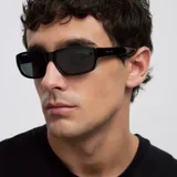 Lentes de sol con diseño rectangular y envolvente, de estilo deportivo. Montura y lentes en color negro, con protección UV400 categoría 3 y lentes polarizadas.