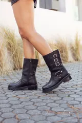 Bota de cuero negra, de caña media, con hebillas decorativas y cierre lateral.