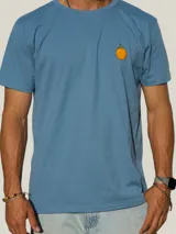 Remera de algodón blanca con cuello redondo y manga corta, presenta un pequeño estampado de un fruto de mburucuyá en el lado izquierdo del pecho.