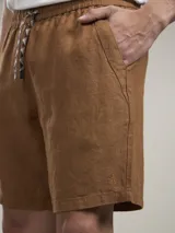 Bermuda de lino color camel, con bolsillos laterales y cintura elástica.