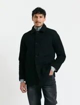 Sobretodo corto de paño en color azul marino, con cuello camisero, cierre frontal mediante botones y manga larga.